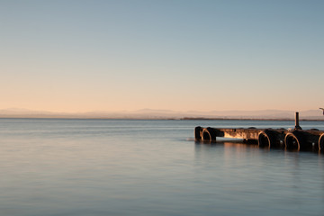 Obraz premium Sunset on a lake with an empty jetty and feeling of calm in the coastal lagoon of Valencia