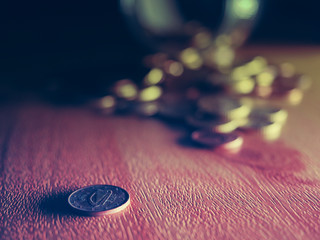 Coins from a glass bottle on a wooden table and dark background., Concept extreme time to reach for savings.