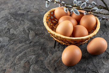 Fresh organic farm eggs lie in a basket on a stone plate, close-up, selective focus, shallow depth of field. Concept, healthy eating, spring religious holidays.