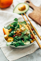 Healthy salad with persimmon, arugula, nuts and feta cheese. Fitness food. Superfoods Vitamin autumn persimmon salad.