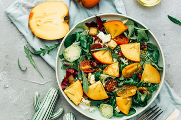 Fresh autumn salad with persimmon, arugula, cheese