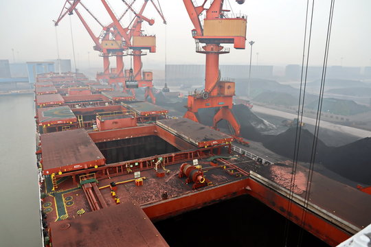 Cargo terminal for discharging coal cargos by shore cranes during foggy weather. Port Bayuquan,China. January, 2020.