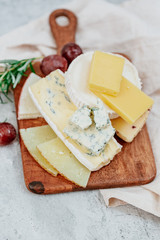 Wooden board with different kinds of delicious cheese on table
