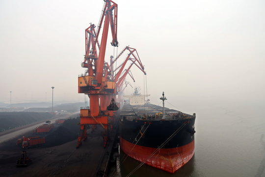 Cargo terminal for discharging coal cargos by shore cranes during foggy weather. Port Bayuquan,China. January, 2020.