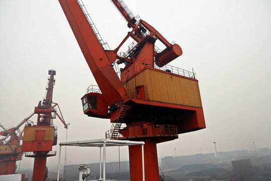 Cargo terminal for discharging coal cargos by shore cranes during foggy weather. Port Bayuquan,China. January, 2020.