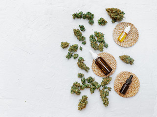 Top view of medical marijuana buds near bottles with hemp oil on white background. Detail of cannabis bud (crimson strain) - medical marijuana concept