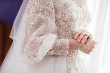 cropped fashion photo of beautiful bride in elegant wedding dress in room near window in the wedding morning