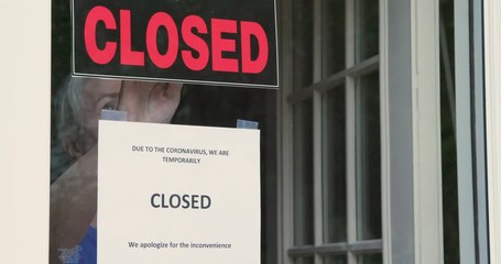A small business owner turns the sign on her storefront from open to closed because of coronavirus.