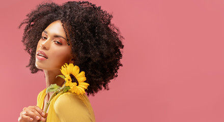 Beauty afro woman posing with sunflower.