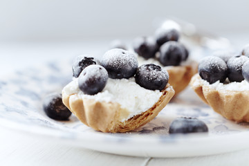 Little mascarpone tart with fresh bilberries on bright background. Close up.	