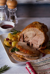 Roast turkey leg with potatoes, cranberries and rosemary on white plate. vertical image
