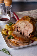 Roast turkey leg with potatoes, cranberries and rosemary on white plate. vertical image