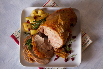 Roast turkey leg with potatoes, cranberries and rosemary on white plate. Flat lay, overhead horizontal image