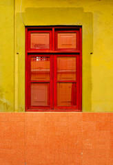A simple single closed window in a bright painted wall.