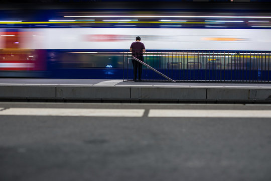 People in a trainstation with motion blurred trains moving fast (color toned image)