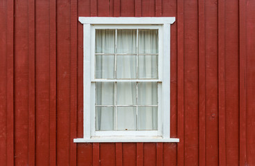 Obraz na płótnie Canvas Facade with red brown colored wood and a white window frame with curtain, Telegraph Cove, Vancouver Island, British Columbia, Canada.