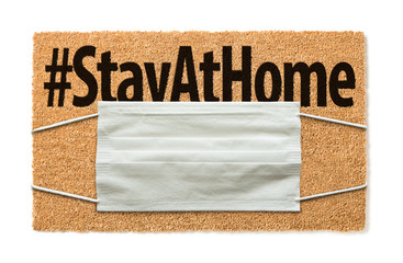 Welcome Mat With Medical Face Mask and #Stay At Home Text Isolated on White Amidst The Coronavirus Pandemic