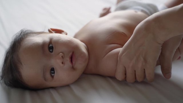 Mother hands massage small baby arm when lying on bed