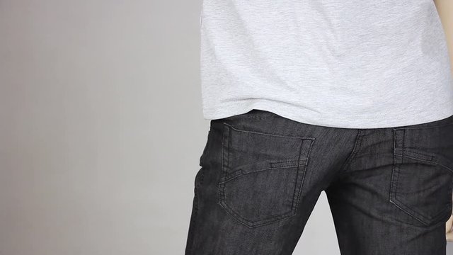 pickpocket gently takes out leather  wallet from someones black pants back pocket by two fingers, pickpocketing theft crime, close-up
