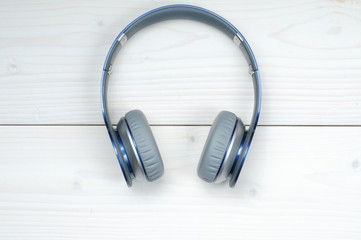Blue and silver modern headphones on a white wooden background