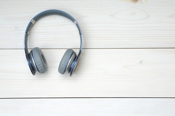 Blue and silver modern headphones on a white wooden background