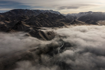 Aerial landscape short after autumn sunrise over the Kurmduk Valley in the vicinity of the Ak-Sai Valley and Kol Suu lake, showing the Kurumduk River through the Kyrgyz Tian Shan Mountains