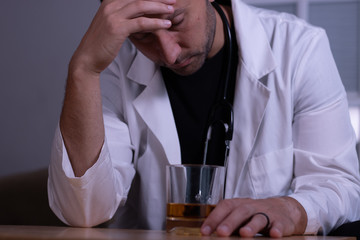 Tired and stressed doctor drinking whiskey