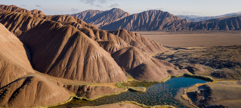 aerial landscape of the amazing Ozero Torpo, a lake surrounded by eroded mud hills along the Mels-Ashu pass connection Tash-Rabat at the village of Baetov