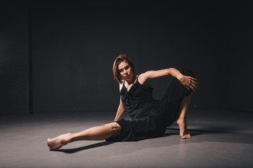 Fototapeta na wymiar Portrait of a beautiful woman dancing on black background. Ballet and contemporary dancer dancing on dark backdrop. Contemporary Art. Plastic and flexible girl in black clothes posing on a black wall