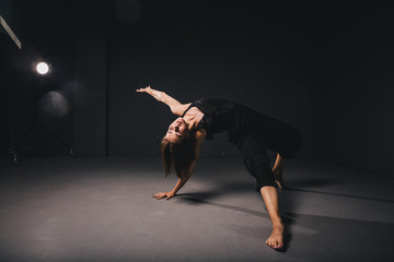 Portrait of a beautiful woman dancing on black background. Ballet and contemporary dancer dancing on dark backdrop. Contemporary Art. Plastic and flexible girl in black clothes posing on a black wall