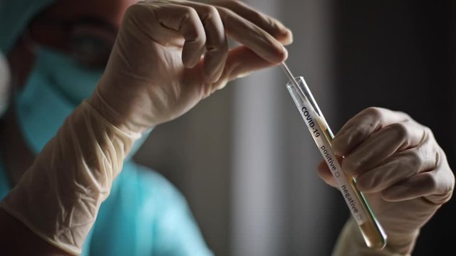 Conceptual video of a doctor holding and looking at a test tube while testing samples for presence of coronavirus (COVID-19).