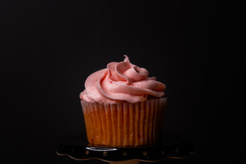 Strawberry cupcake with pink icing on a black background