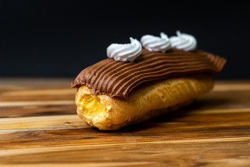 cream filled eclair with chocolate and white icing on a wood board
