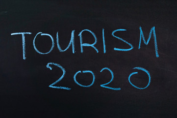 The inscription "tourism 2020" on a black board with blue chalk