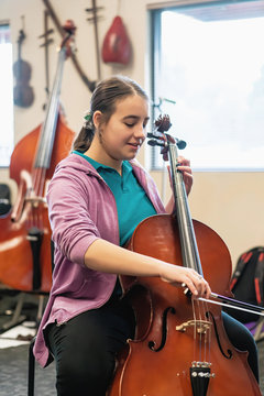 Teenage girl playing cello in classroom