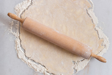 Fresh pastry being rolled out with a rolling pin in the kitchen on a marble pastry board