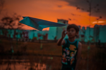 Niño lanzando avión de papel 