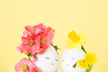 Obraz na płótnie Canvas Lovely couple of Easter eggs with drawn faces closed their eyes, decorated with spring flower and wildflowers. Creative concept