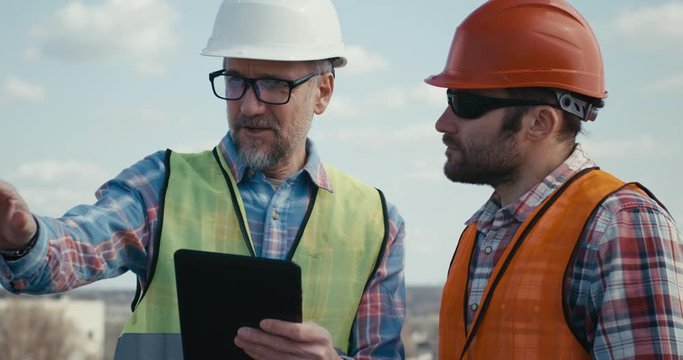 Engineer and technician discussing on rooftop