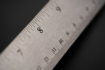Metal ruler on a black leather isolated background with black numbers and scale. Show scale in black digit.