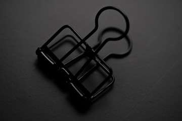 Black paper clip on black background.