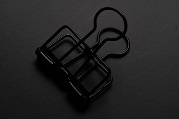 Black paper clip on black background.