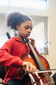 Teenage girl playing cello in classroom