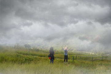 Tourists on green grass hill with thick fog