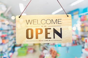 A business sign that says open on cafe or restaurant hang on door at entrance.