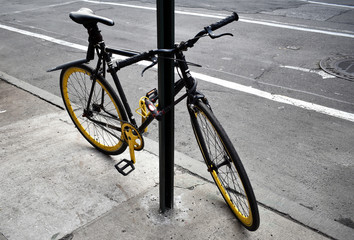 Fototapeta na wymiar Yellow bicycle chained to a pole on a street in Manhattan, New York
