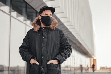 Men wears a black protective medical face mask being in the city during a coronavirus pandemic....