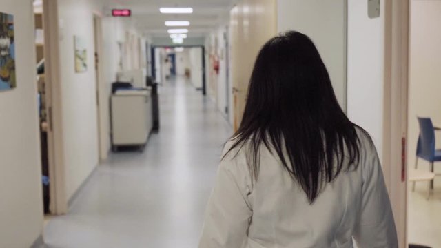 young female doctor walks in an empty hospital ward, slow motion