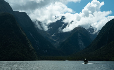 Fototapeta na wymiar Rolling clouds come over a mountain at the fjord Milford Sound in New Zealand