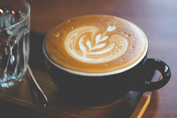 Close up of cup of hot latte art coffee served with cold water